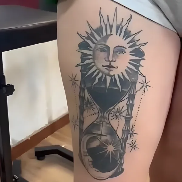 Sol con cara sobre un reloj de arena, en el muslo